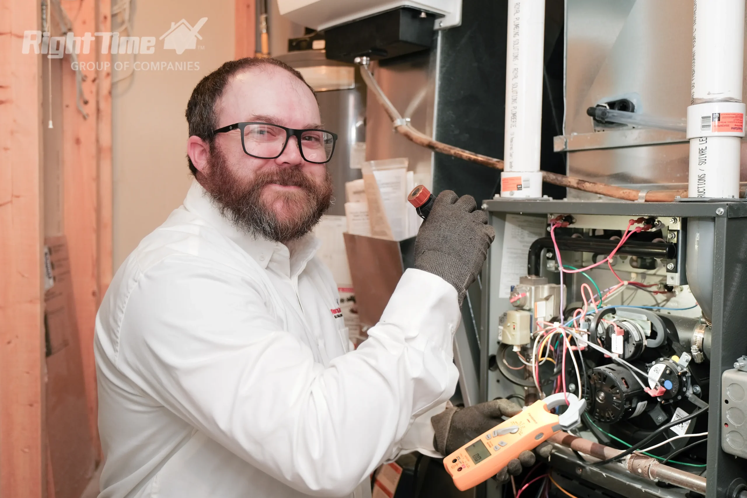 HVAC technician troubleshooting an open gas furnace with a multimeter in a basement.