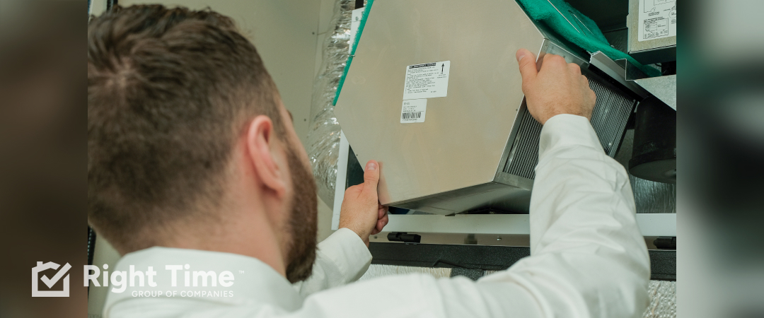 HVAC technician removing a whole-home air filter from an air handler during service to support cleaner indoor air and steady summer cooling during the Edmonton smoke season.
